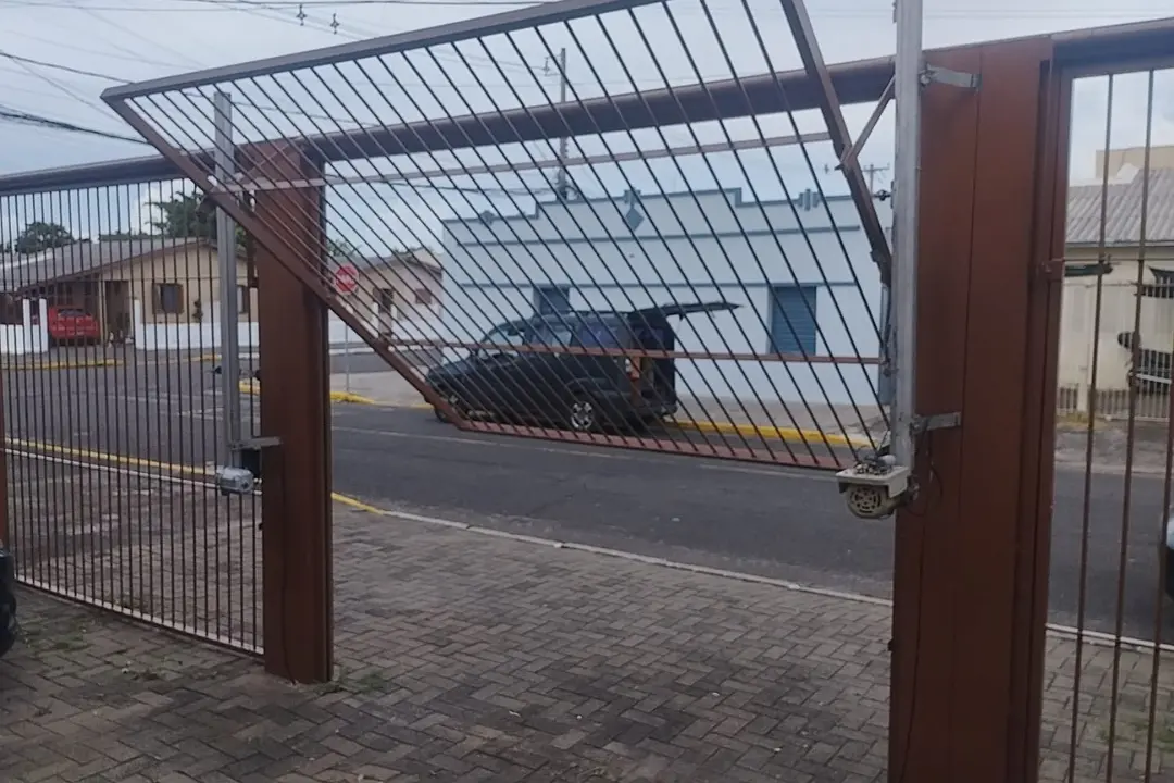 Portão eletrônico basculante de elevação abrindo perfeitamente com veículo utilitário estacionado na garagem em Canoas.