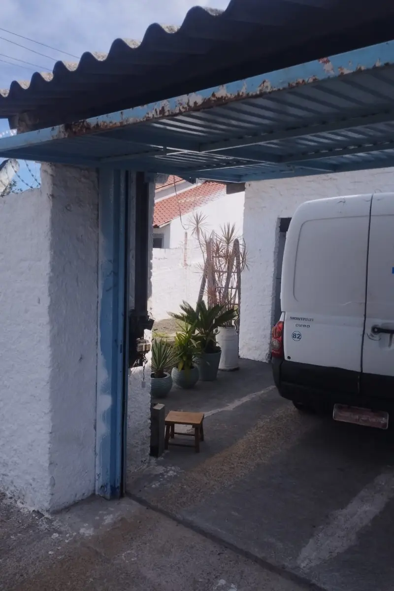 Estrutura lateral de um portão eletrônico basculante aberto em uma garagem residencial, com um veículo utilitário estacionado no interior.